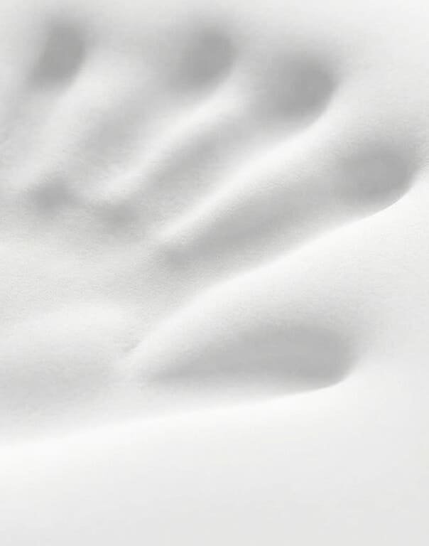 Handprint slowly recovering on the memory foam surface of the pillow